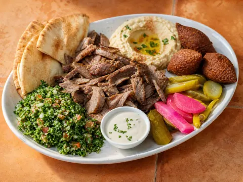 Representative a Lebanese lamb shawarma platter with kibbeh, hummus, tabbouleh, pickles, garlic sauce, and pita selected for Lebanese Butcher