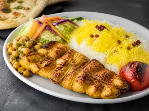 Representative an Afghan chicken kabob platter with saffron rice, chickpeas, roasted tomato, salad, and naan selected for Loudoun Kabob