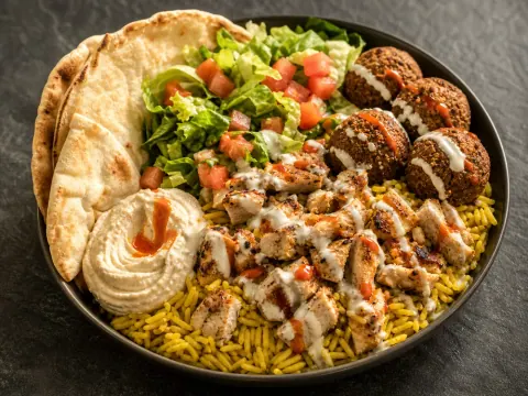 Representative a falafel and chicken platter with yellow rice, lettuce, tomato, pita, hummus, white sauce, and hot sauce selected for The Halal Guys (Fairfax)